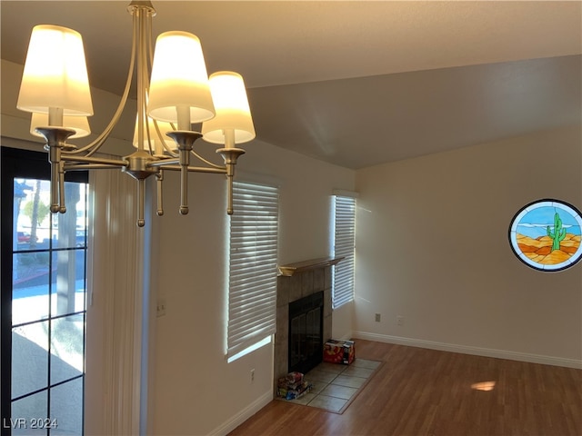 unfurnished living room with hardwood / wood-style flooring, a notable chandelier, and a tile fireplace