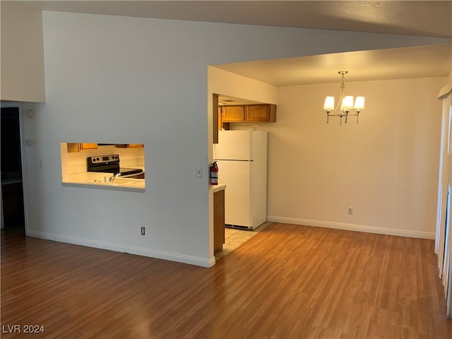 interior space featuring hanging light fixtures, an inviting chandelier, white refrigerator, electric stove, and light wood-type flooring