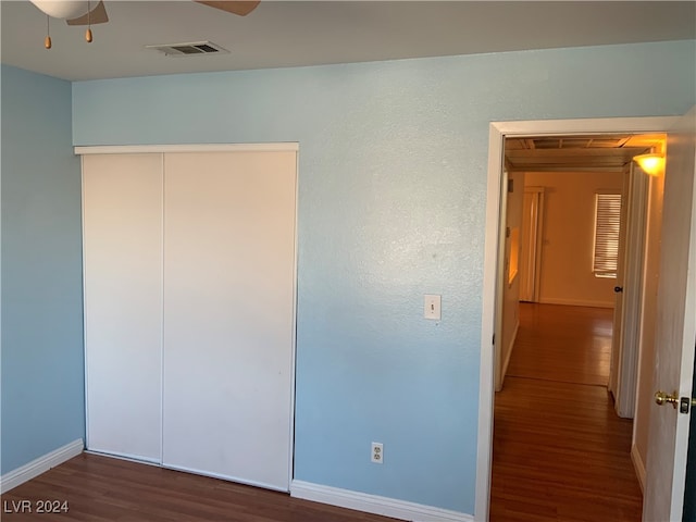 unfurnished bedroom featuring ceiling fan, dark hardwood / wood-style flooring, and a closet