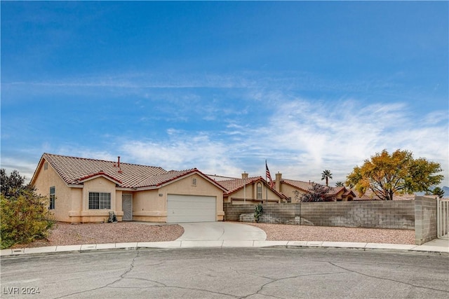 view of front of house with concrete driveway, fence, an attached garage, and stucco siding