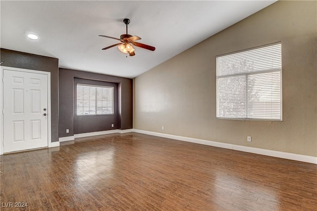 spare room featuring dark wood-type flooring, vaulted ceiling, and baseboards