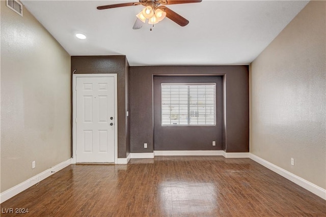 spare room with dark wood-style flooring, visible vents, ceiling fan, and baseboards