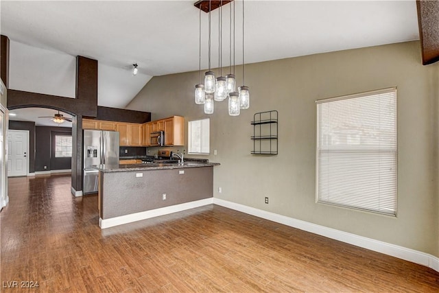 kitchen with decorative light fixtures, appliances with stainless steel finishes, brown cabinetry, wood finished floors, and a peninsula