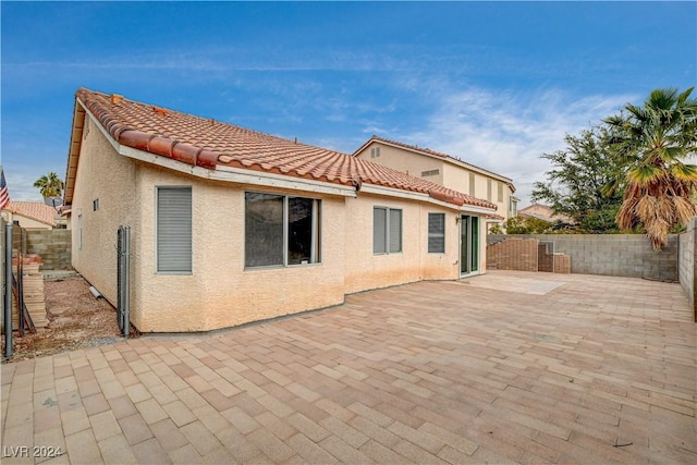 back of property with a fenced backyard, a patio area, a tiled roof, and stucco siding