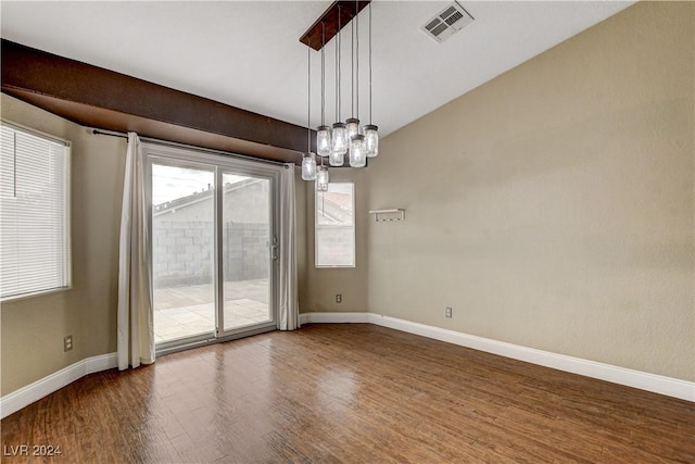 empty room with an inviting chandelier, baseboards, visible vents, and wood finished floors