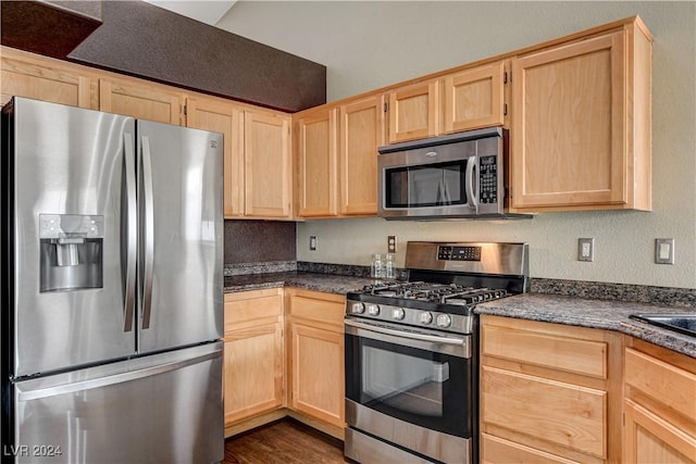 kitchen with dark countertops, light brown cabinets, appliances with stainless steel finishes, and dark wood finished floors