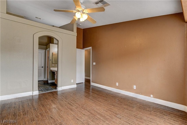 spare room with baseboards, visible vents, dark wood finished floors, arched walkways, and ceiling fan