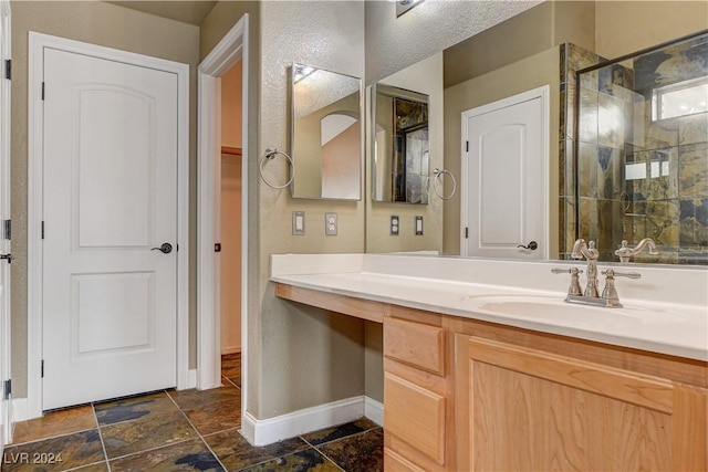 bathroom with a stall shower, stone finish flooring, vanity, and baseboards