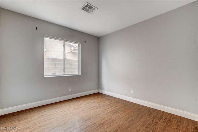 empty room featuring visible vents, baseboards, and wood finished floors