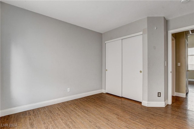 unfurnished bedroom with a closet, baseboards, and wood finished floors