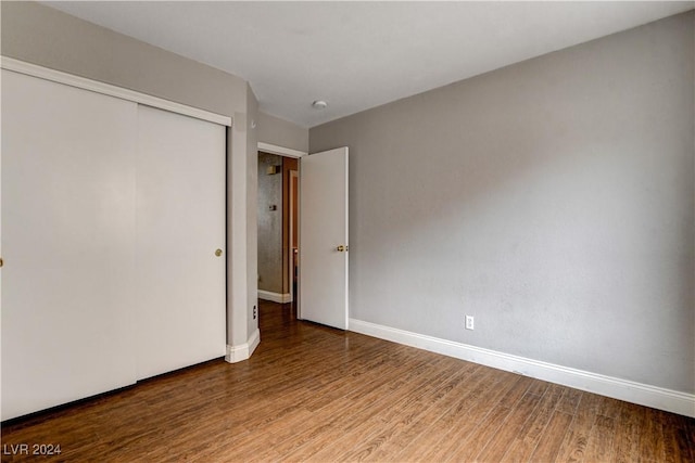 unfurnished bedroom with a closet, baseboards, and wood finished floors