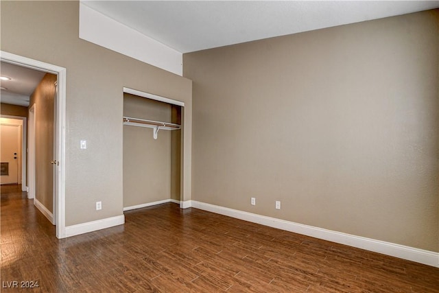 unfurnished bedroom featuring dark wood-style floors, a closet, and baseboards