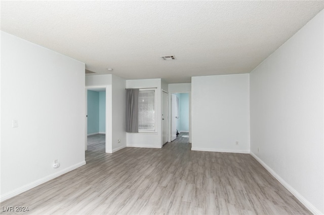 unfurnished room with light hardwood / wood-style floors and a textured ceiling