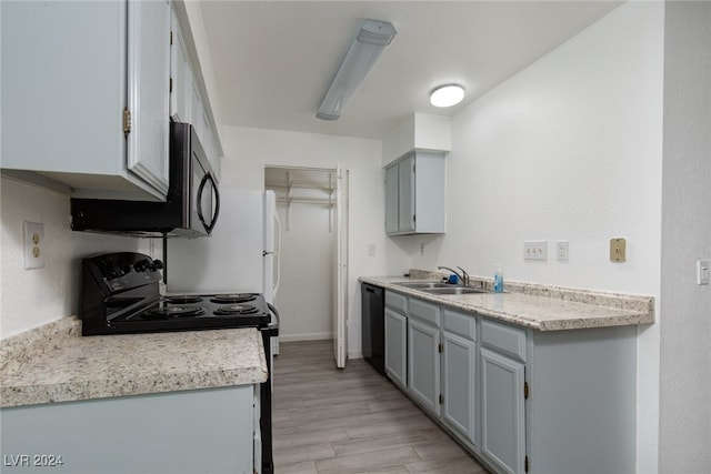 kitchen with sink, light hardwood / wood-style floors, gray cabinetry, and black appliances