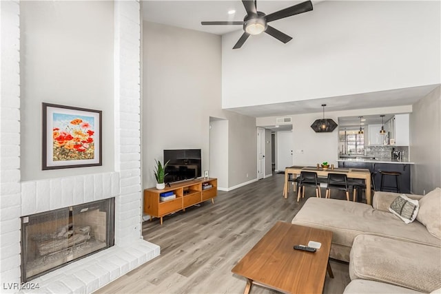 living room with ceiling fan, a fireplace, and light wood-type flooring