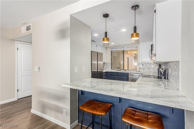 kitchen with white cabinetry, stainless steel appliances, a kitchen bar, and kitchen peninsula