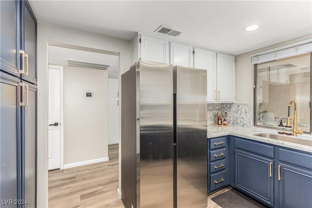 kitchen with sink, blue cabinetry, stainless steel refrigerator, tasteful backsplash, and white cabinets