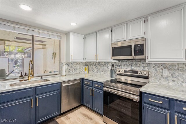 kitchen featuring appliances with stainless steel finishes, a textured ceiling, blue cabinets, sink, and white cabinets