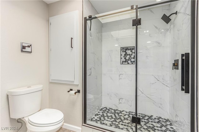 bathroom featuring a shower with shower door and toilet