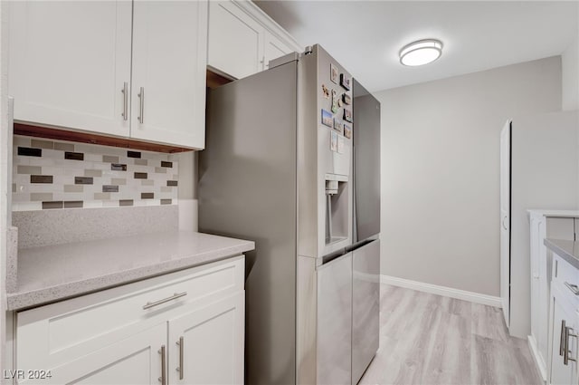 kitchen featuring decorative backsplash, white cabinetry, light wood-type flooring, and stainless steel fridge with ice dispenser