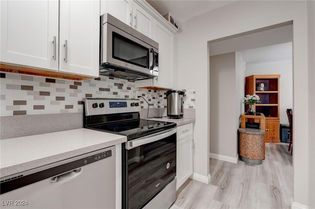 kitchen featuring tasteful backsplash, white cabinets, light hardwood / wood-style floors, and appliances with stainless steel finishes