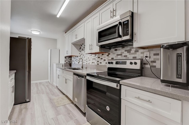 kitchen with white cabinets, appliances with stainless steel finishes, light hardwood / wood-style flooring, and sink