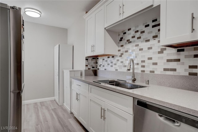 kitchen featuring white cabinets, sink, appliances with stainless steel finishes, tasteful backsplash, and light hardwood / wood-style floors