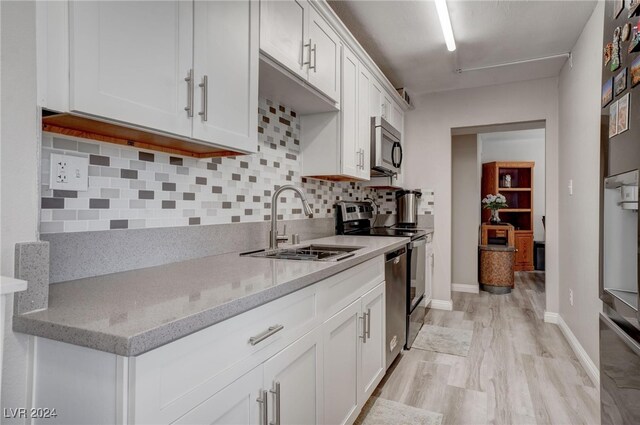 kitchen featuring light stone countertops, tasteful backsplash, stainless steel appliances, light hardwood / wood-style flooring, and white cabinets