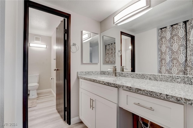 bathroom with vanity, toilet, wood-type flooring, and a textured ceiling