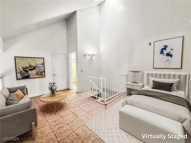 bedroom featuring ensuite bathroom, light tile patterned floors, and high vaulted ceiling