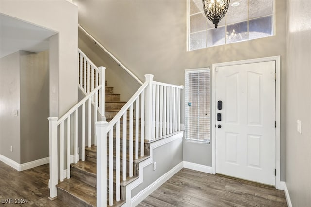 foyer with a chandelier, wood-type flooring, a wealth of natural light, and a high ceiling