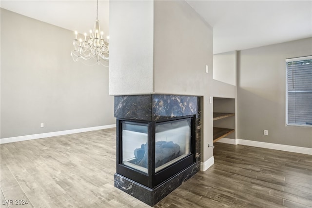 room details with a fireplace, wood-type flooring, and an inviting chandelier