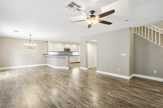 unfurnished living room featuring ceiling fan with notable chandelier and hardwood / wood-style flooring