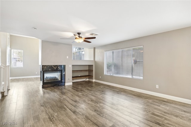 unfurnished living room featuring a multi sided fireplace, hardwood / wood-style floors, and ceiling fan