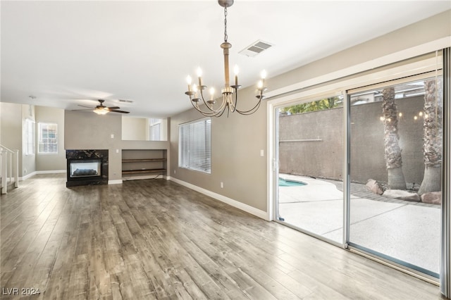 unfurnished living room with ceiling fan with notable chandelier, wood-type flooring, and a premium fireplace