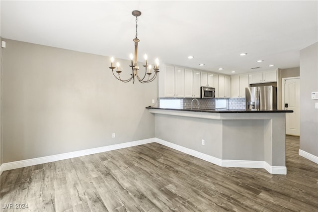 kitchen with pendant lighting, hardwood / wood-style flooring, white cabinetry, kitchen peninsula, and stainless steel appliances