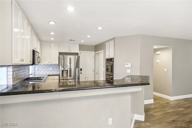 kitchen featuring white cabinets, kitchen peninsula, hardwood / wood-style floors, and appliances with stainless steel finishes