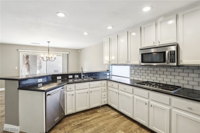 kitchen featuring kitchen peninsula, stainless steel appliances, white cabinets, and a healthy amount of sunlight