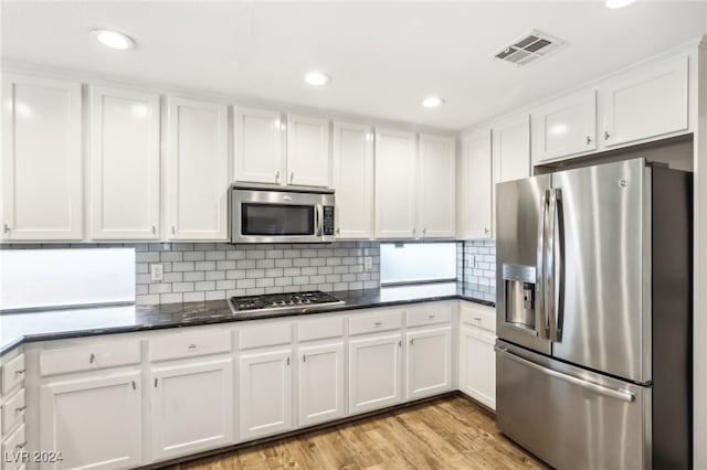 kitchen featuring tasteful backsplash, white cabinetry, stainless steel appliances, and light hardwood / wood-style floors