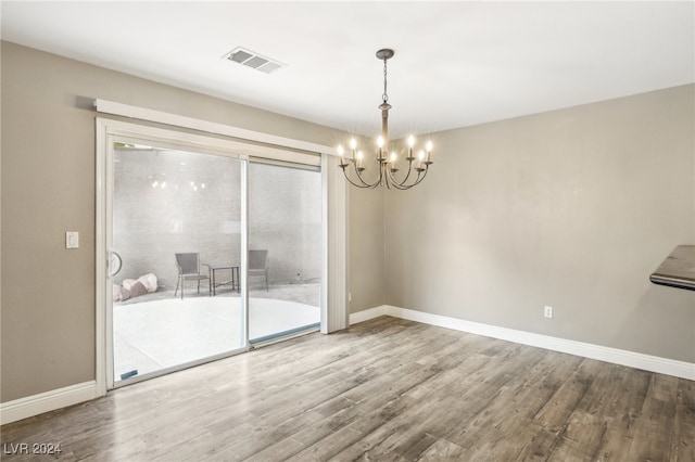 unfurnished room featuring hardwood / wood-style flooring and a notable chandelier