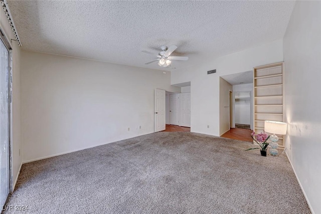 unfurnished bedroom featuring carpet, ceiling fan, a spacious closet, a closet, and a textured ceiling