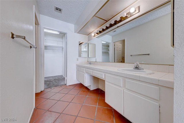 full bathroom featuring a spacious closet, a textured ceiling, and a sink