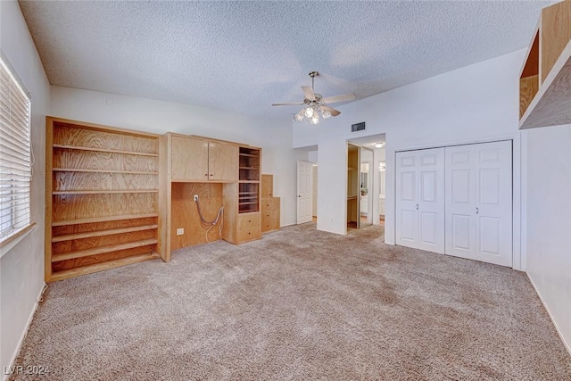 unfurnished bedroom with visible vents, light colored carpet, lofted ceiling, a closet, and a textured ceiling