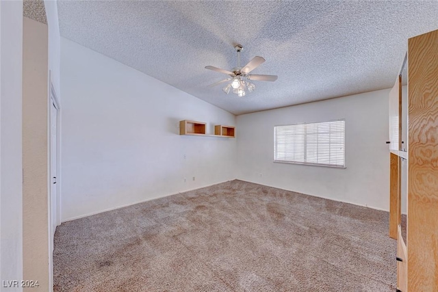 empty room with carpet flooring, a textured ceiling, lofted ceiling, and a ceiling fan