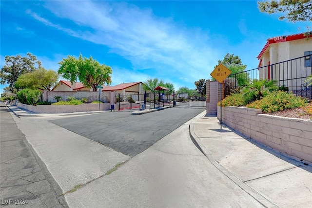 view of street featuring curbs, traffic signs, a gate, a gated entry, and sidewalks