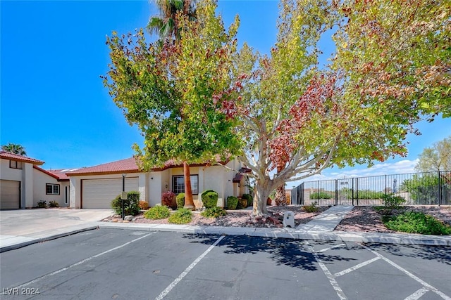 view of front of house featuring a tiled roof, uncovered parking, fence, and stucco siding