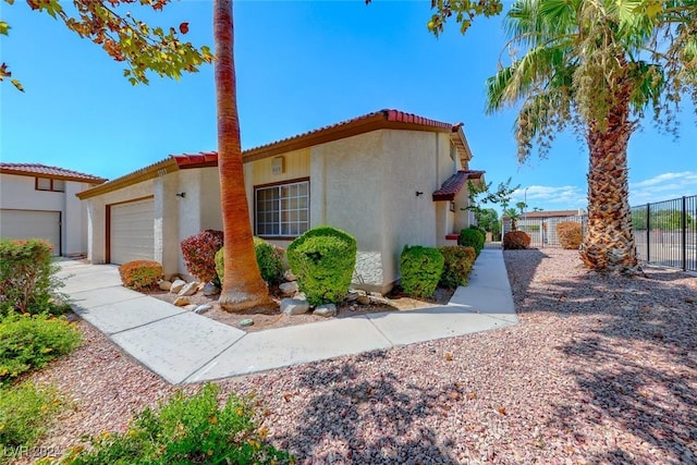 view of front of house with stucco siding, an attached garage, a tile roof, and fence