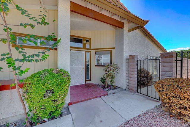 property entrance featuring a tiled roof, a gate, fence, and stucco siding