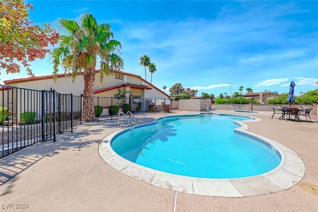 community pool with a patio and fence