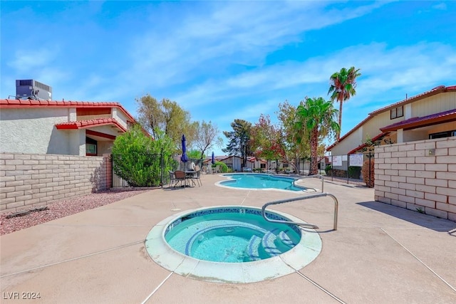 pool featuring a patio area, a hot tub, central AC, and fence